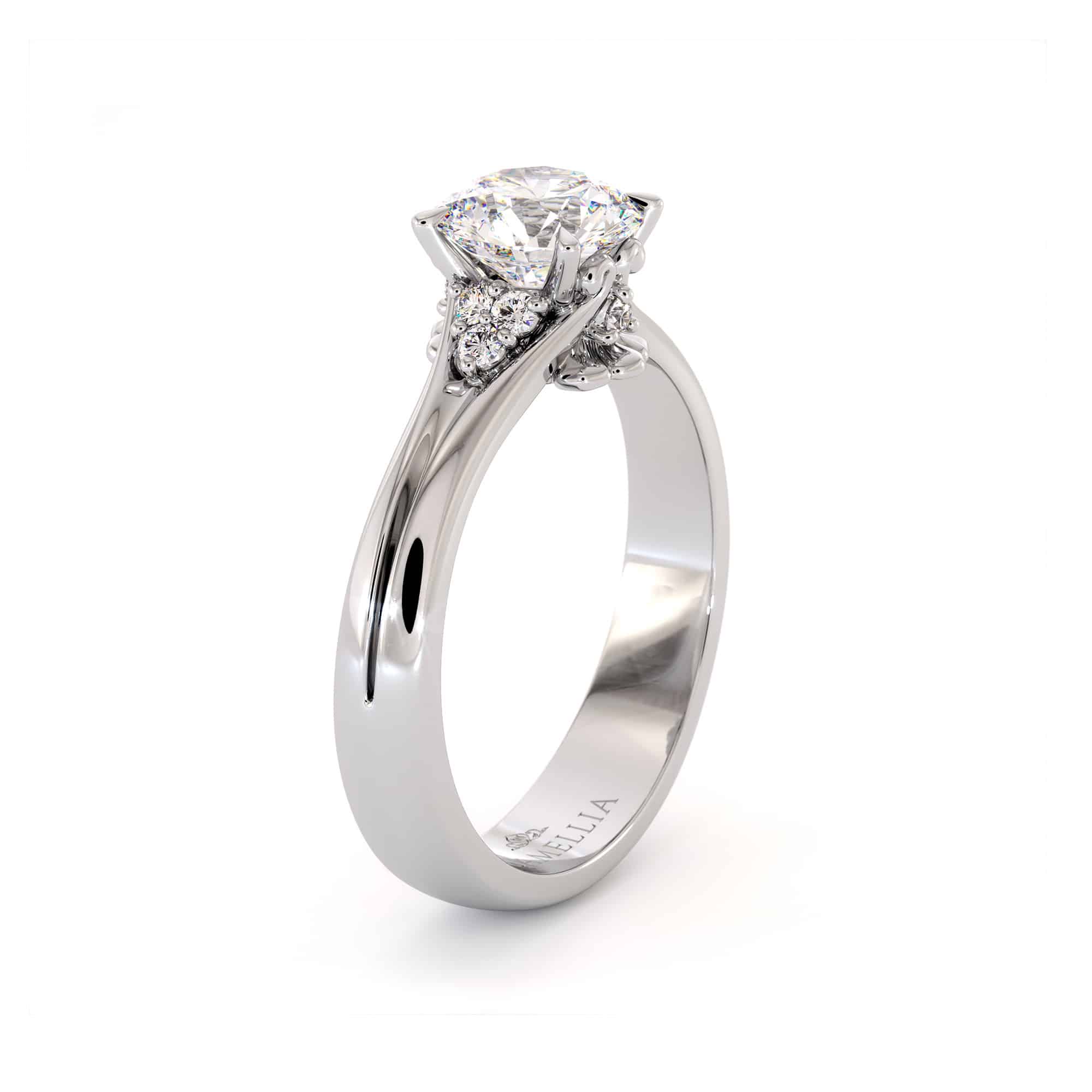 CL-0007A — White Gold, face-up view Round moissanite face-up in white gold, six claws holding the stone above a heart motif underneath