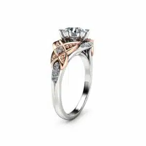An angled view of a two-tone Art Deco engagement ring with a round lab diamond and rose gold accents.