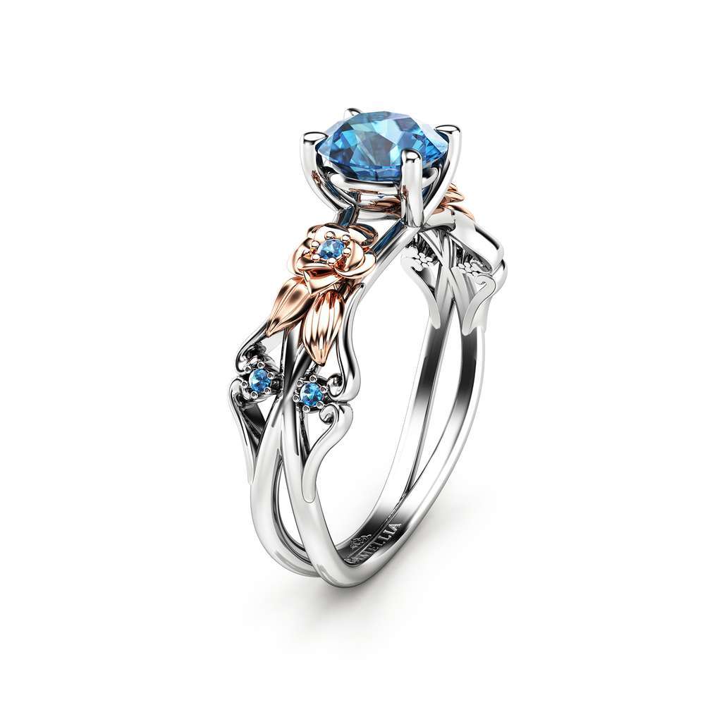 Angled View Petal Blue Diamond Ring An angled view of a floral engagement ring featuring a blue diamond center and rose gold flower petals.