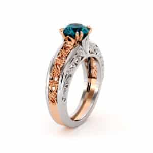 Frontal view of a vintage round blue diamond ring with two-tone gold filigree.