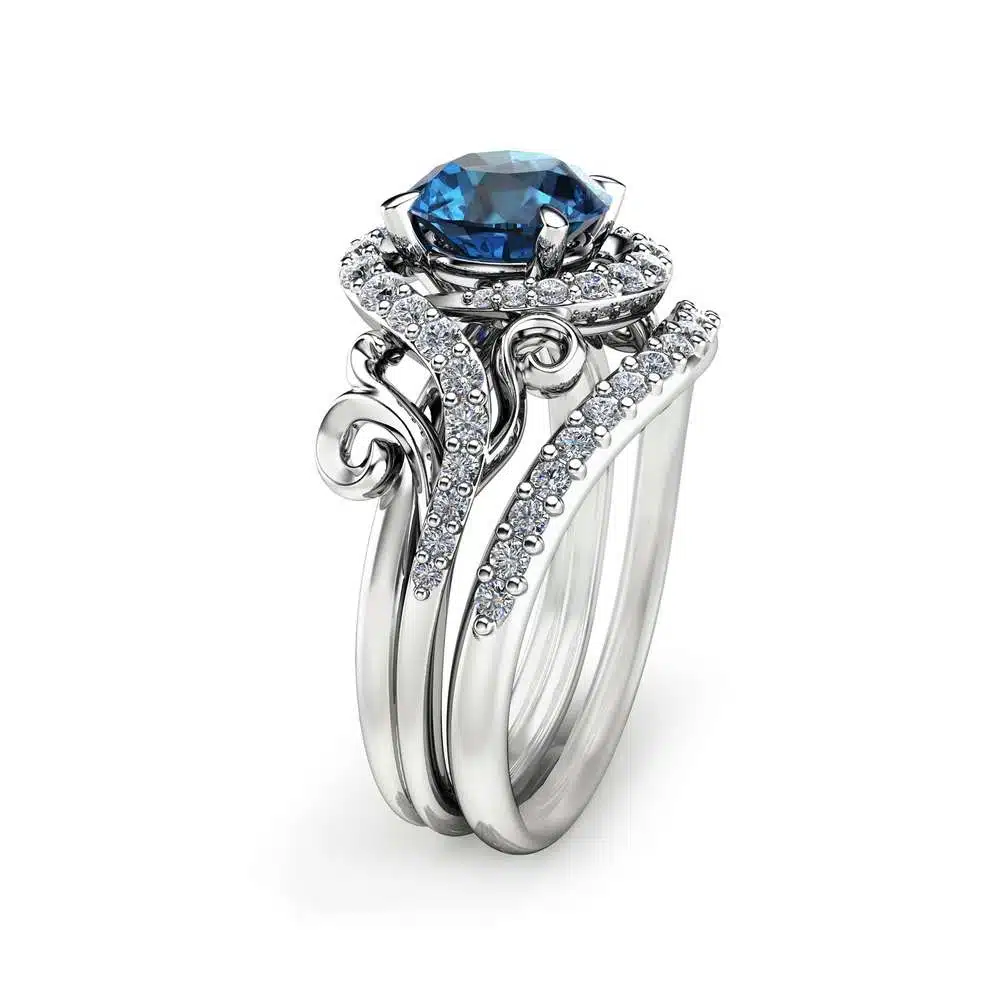 Angled View Swirl Blue Diamond Bridal Set An angled side view of a swirl blue diamond bridal set featuring a halo setting and pavé-set bypass bands.