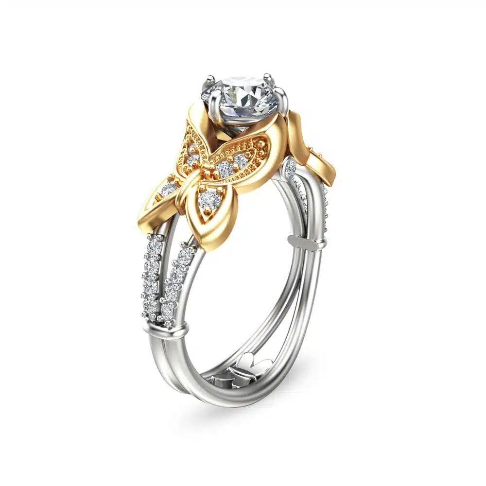 An angled view of a moissanite engagement ring with gold butterflies and a split band.