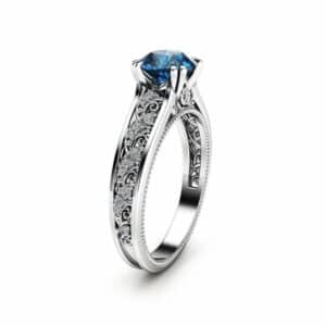 Direct frontal view of a round blue diamond vintage ring with milgrain and side diamond accents.
