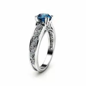 Direct frontal view of a round blue diamond vintage ring with milgrain and side diamond accents.