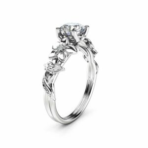 An angled view of a leaf-themed engagement ring with a round diamond center and sculpted branch band.