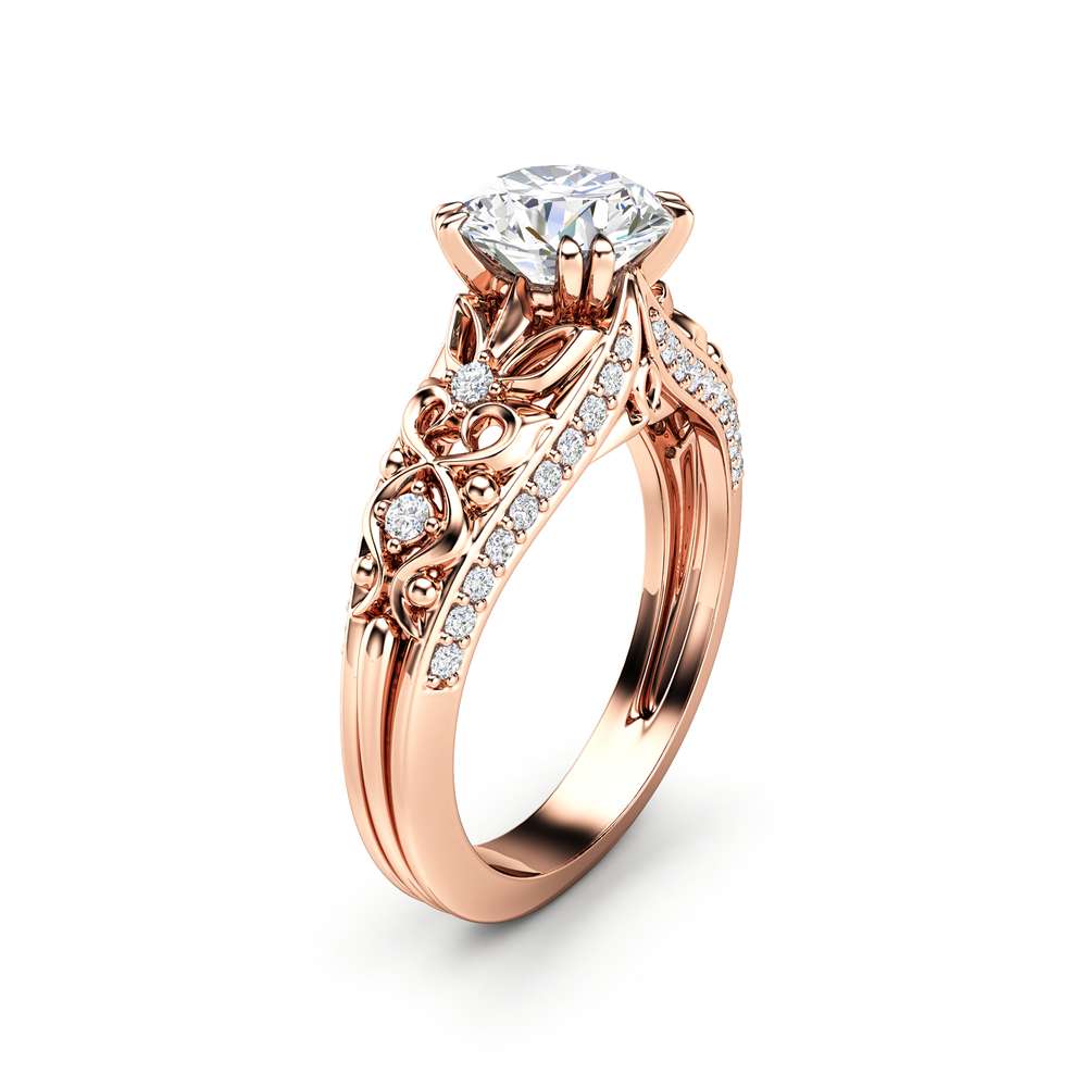 Rose gold vintage filigree ring at three-quarter angle, round moissanite above pave split shoulders