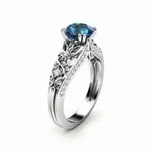 An angled view of an Art Deco ring with a blue diamond and white gold filigree.