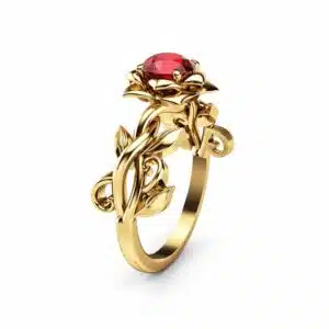 Yellow gold rose ring at three-quarter angle, a natural ruby cupped in petals above a leafy vine