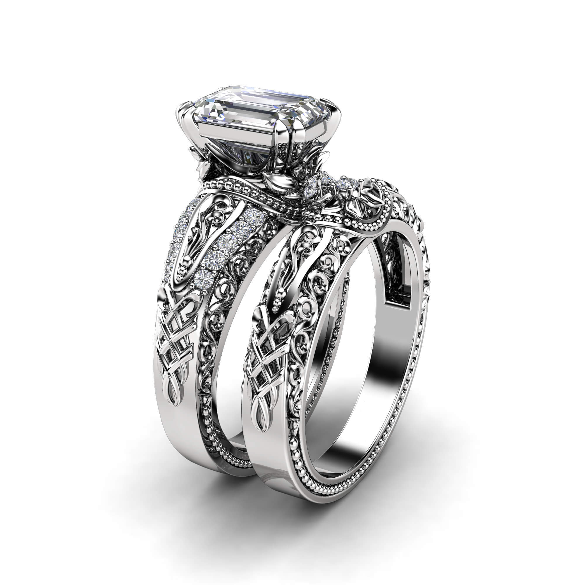 Angled View Majestic Emerald Art Deco Bridal Set An angled view of a white gold emerald-cut diamond bridal set featuring intricate filigree and milgrain detailing.