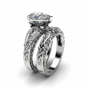 An angled view of a white gold pear-cut diamond bridal set featuring intricate filigree and milgrain detailing.