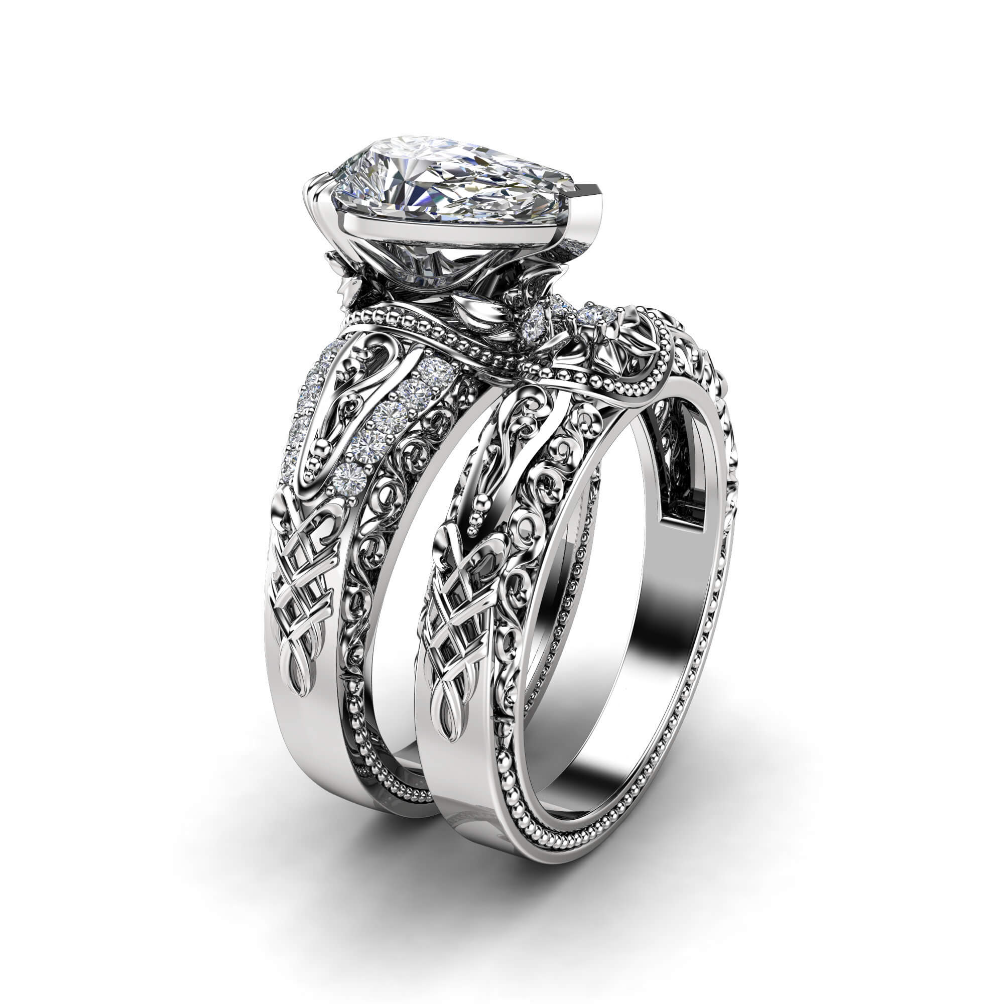 An angled view of a white gold pear-cut diamond bridal set featuring intricate filigree and milgrain detailing.